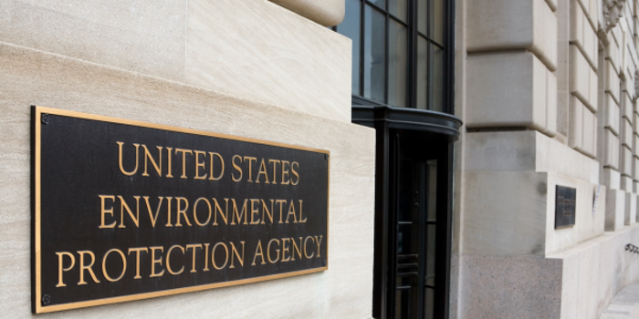 A plaque on the stone wall, bearing "United States Environmental Protection Agency," is positioned near the building's entrance with large windows and a column, where critical testing and assessment of environmental factors like mold are conducted.
